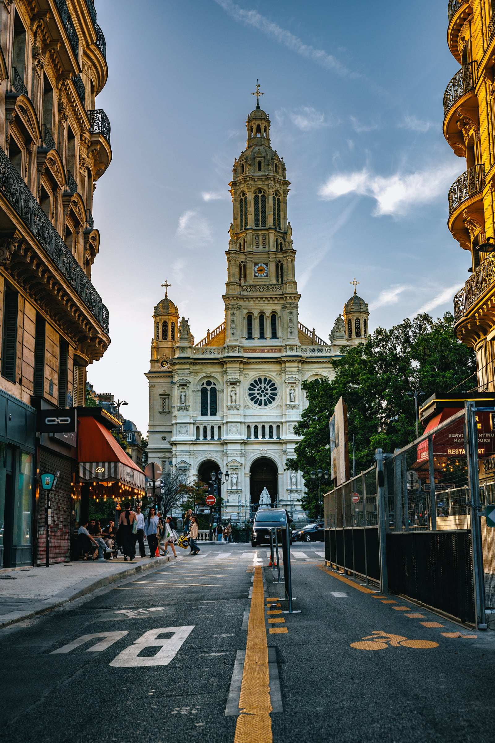 A church tower centered at the end of a narrow city street.