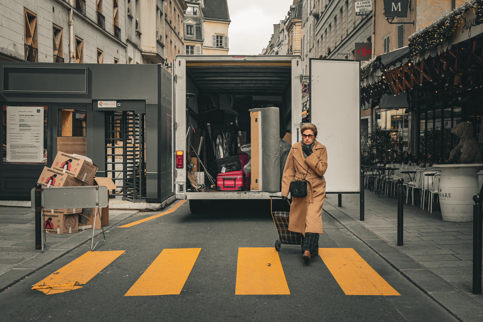 A pedestrian crossing bold yellow markings between pale buildings.