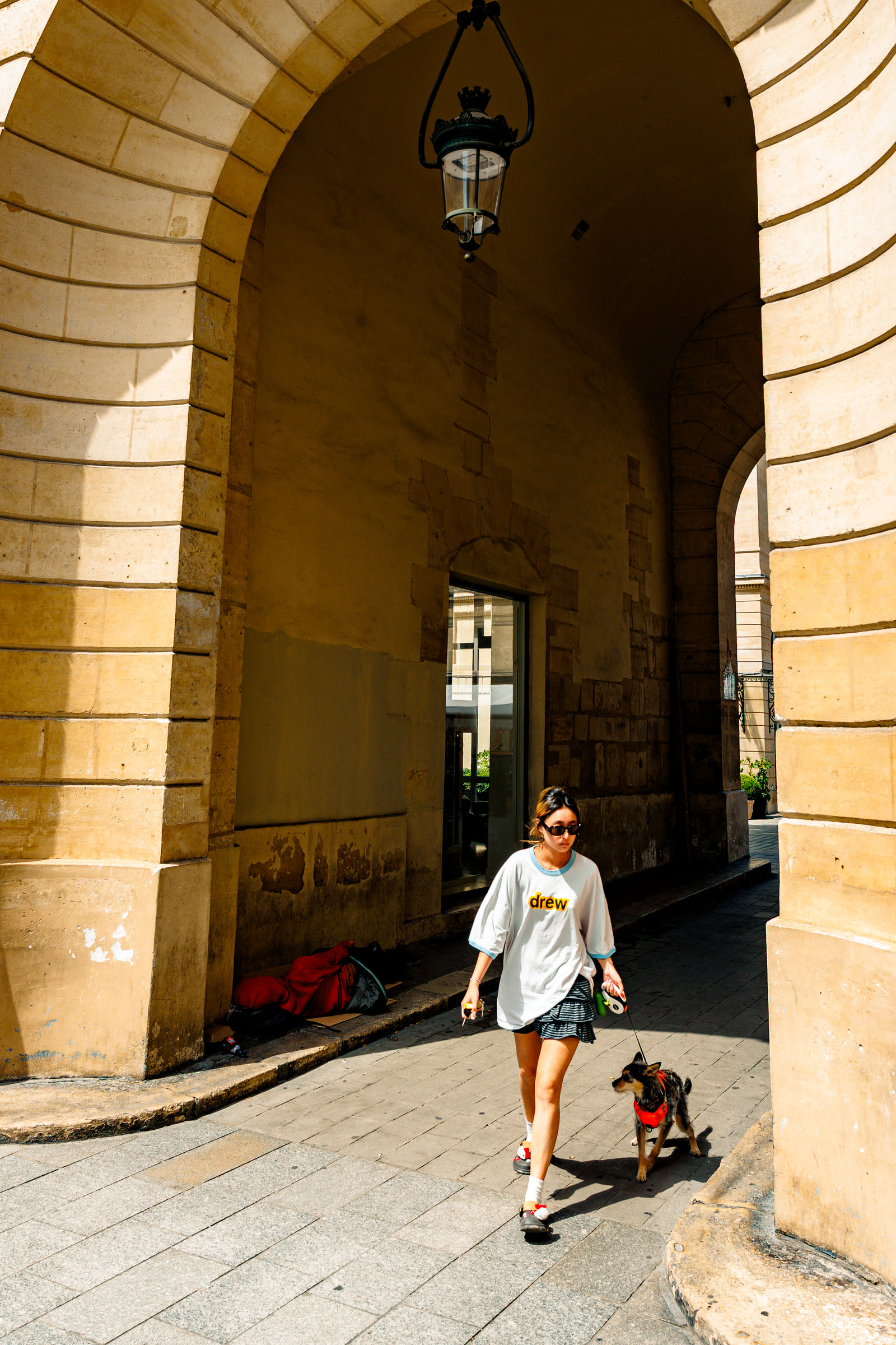 A solitary figure crossing through a monumental stone archway.