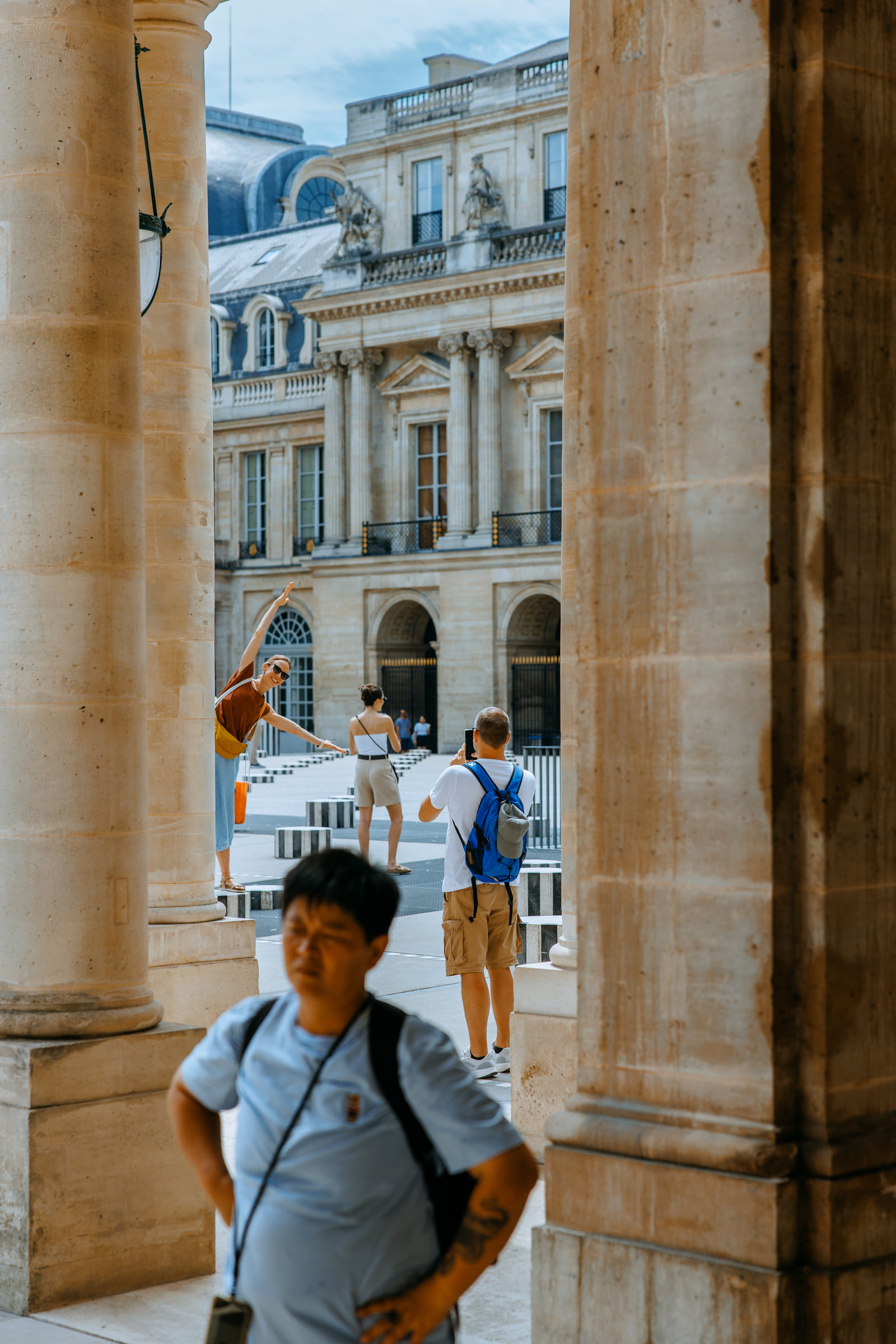 A person framed between tall stone columns and a bright street beyond.