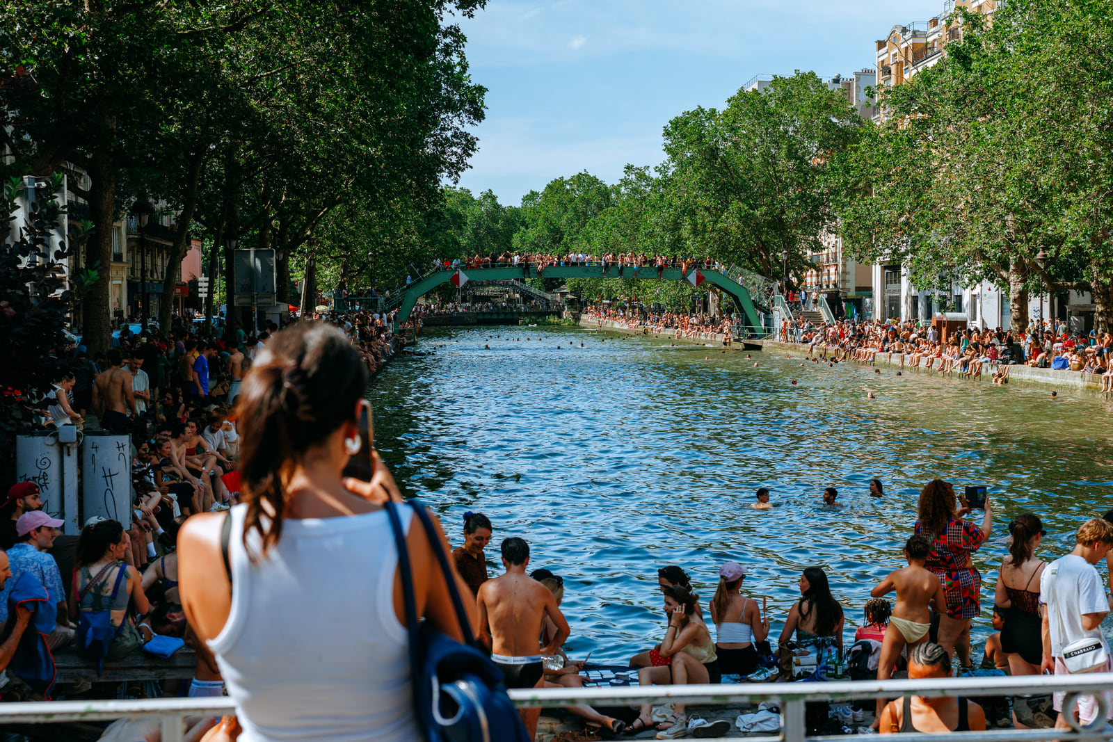 Crowds gathered along both banks of a tree-lined canal.