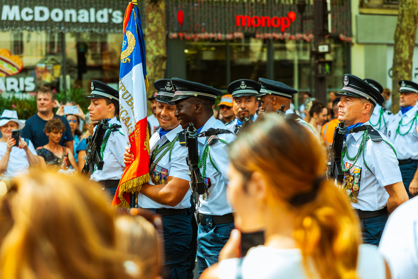 A dense street gathering with flags moving through the crowd.
