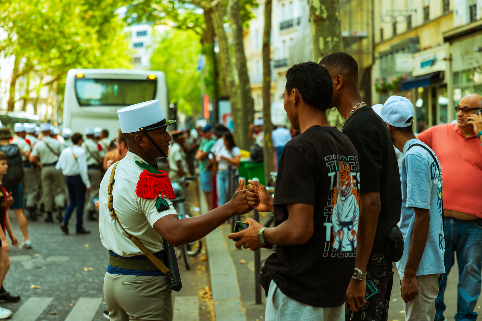 Two people speaking amid a busy sunlit street gathering.
